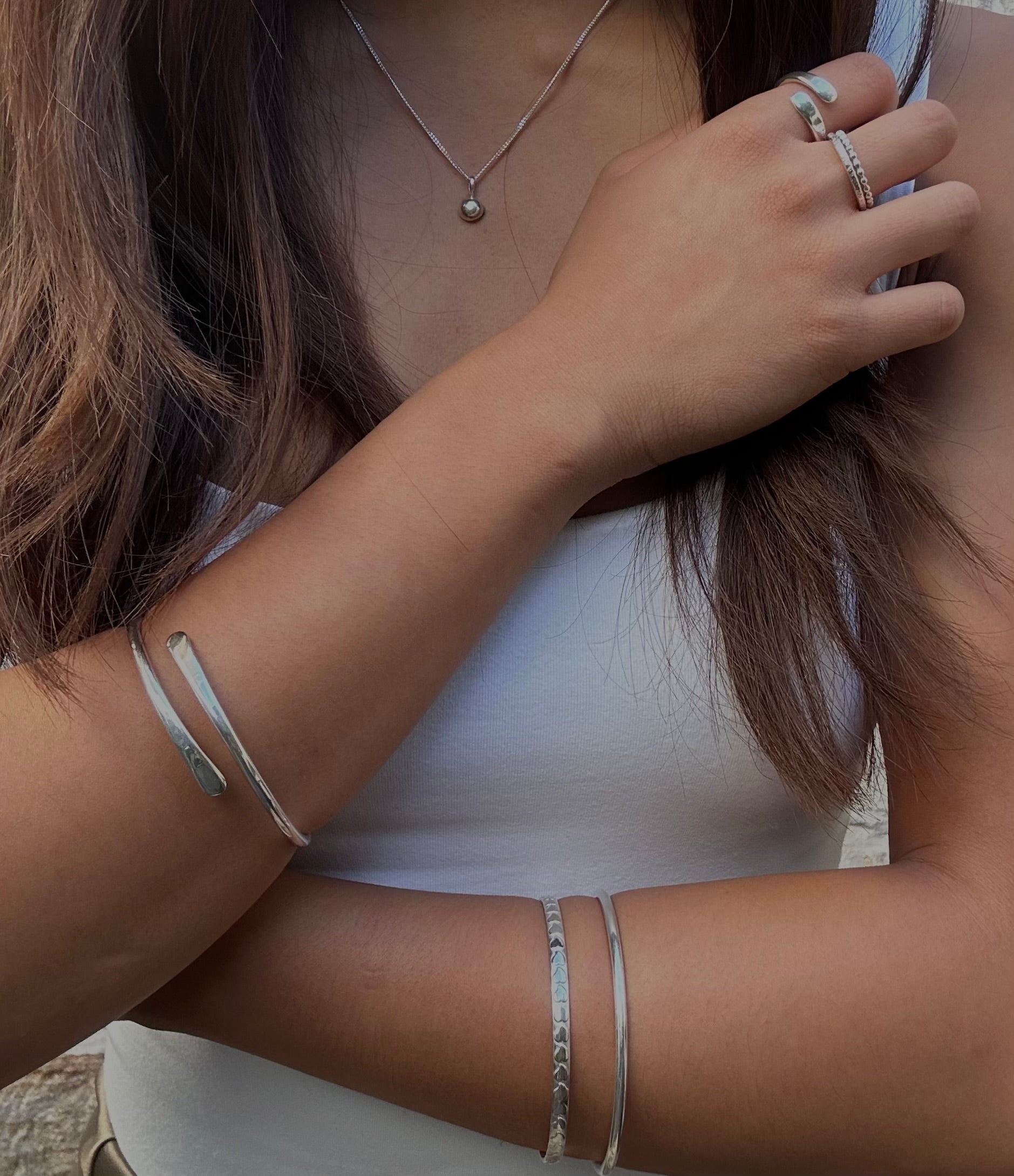 Woman wearing silver bangles, necklace and rings