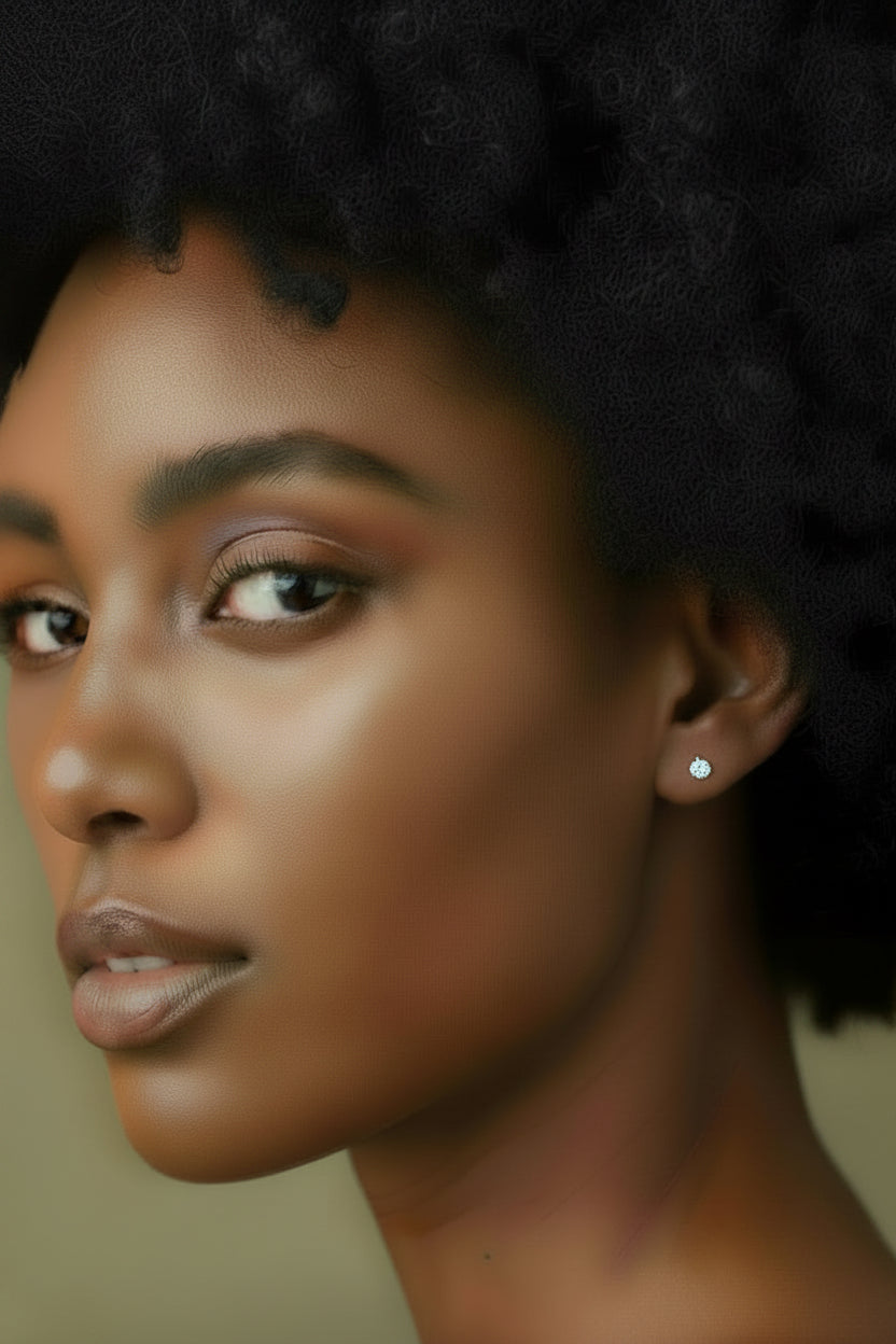 Close-up portrait of a woman with dark curly hair wearing a small silver stud earring with a shiny acquamarine inset