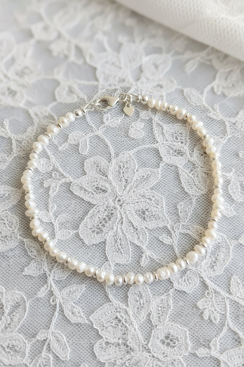Pearl and silver necklace on a lace surface