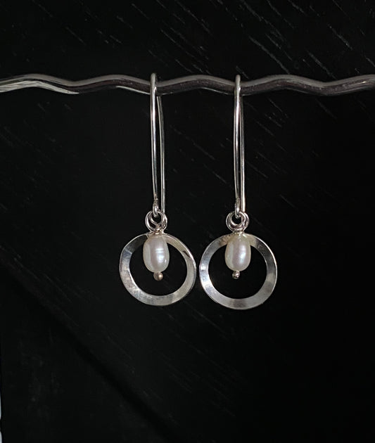 Deco inspired elegant silver circle adorned with a freshwater pearl in the centre, hanging on bespoke ear wires